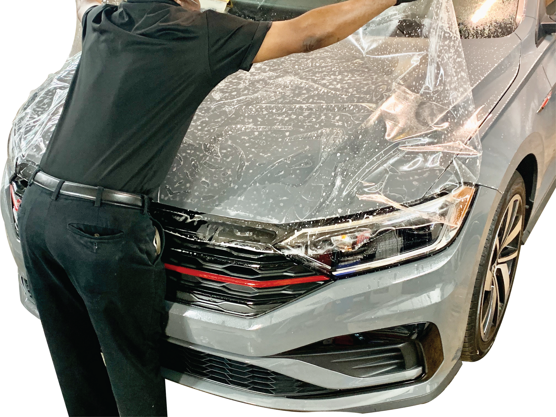 Person wrapping a silver car’s front end in protective plastic film