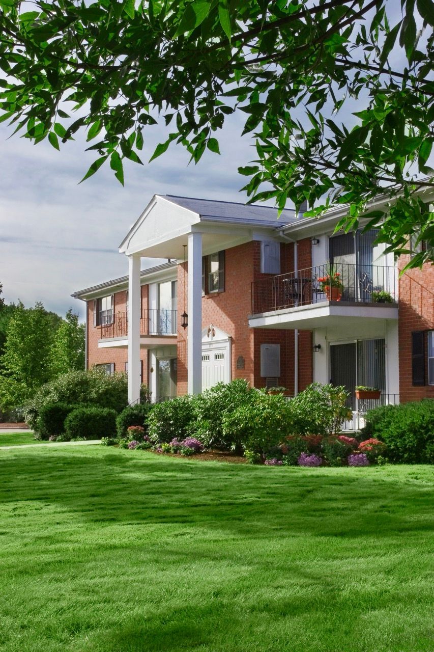 Exterior view of a brick apartment building with well-kept lawn and landscaping.