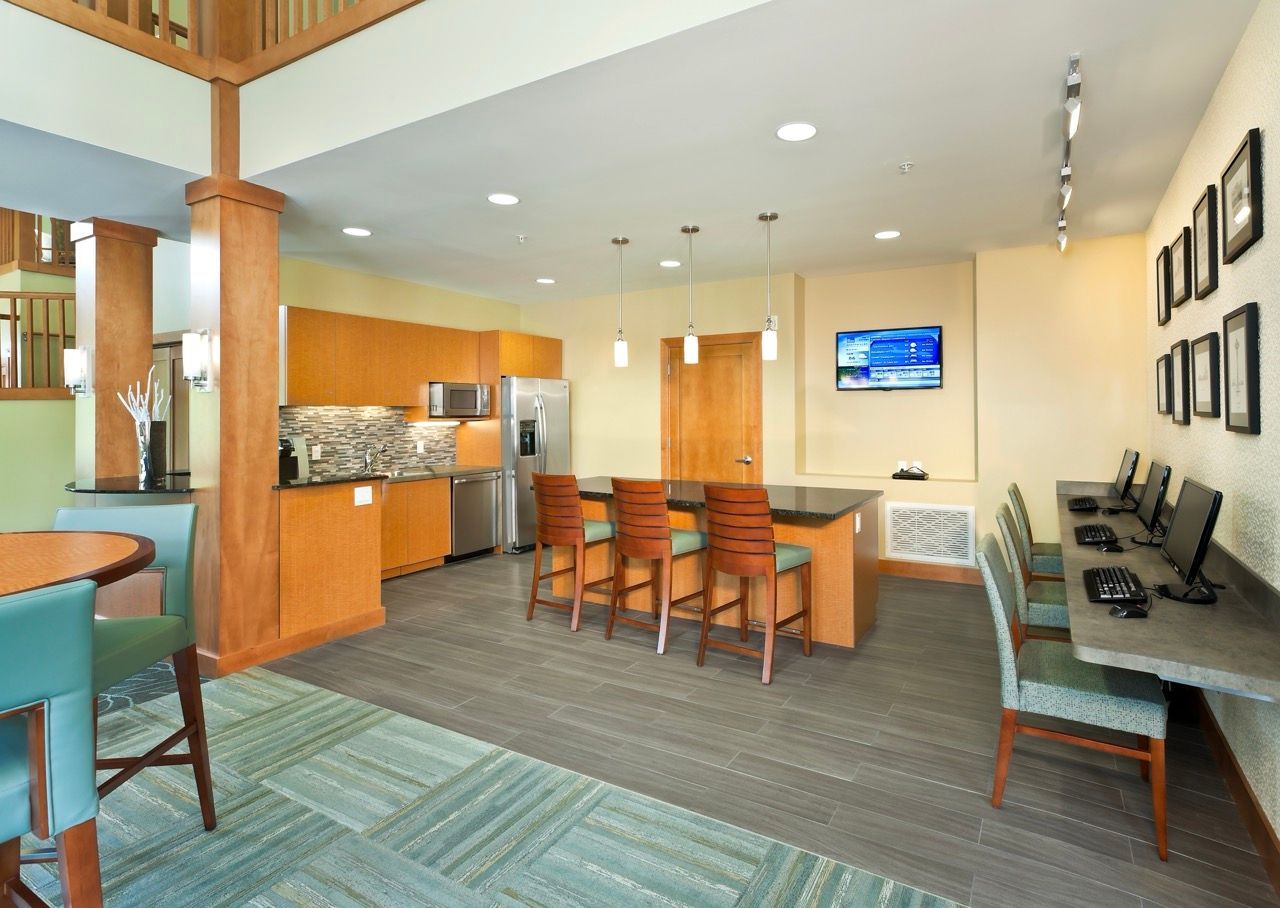 Open communal lounge with kitchen, island, bar stools, and computer workstations.