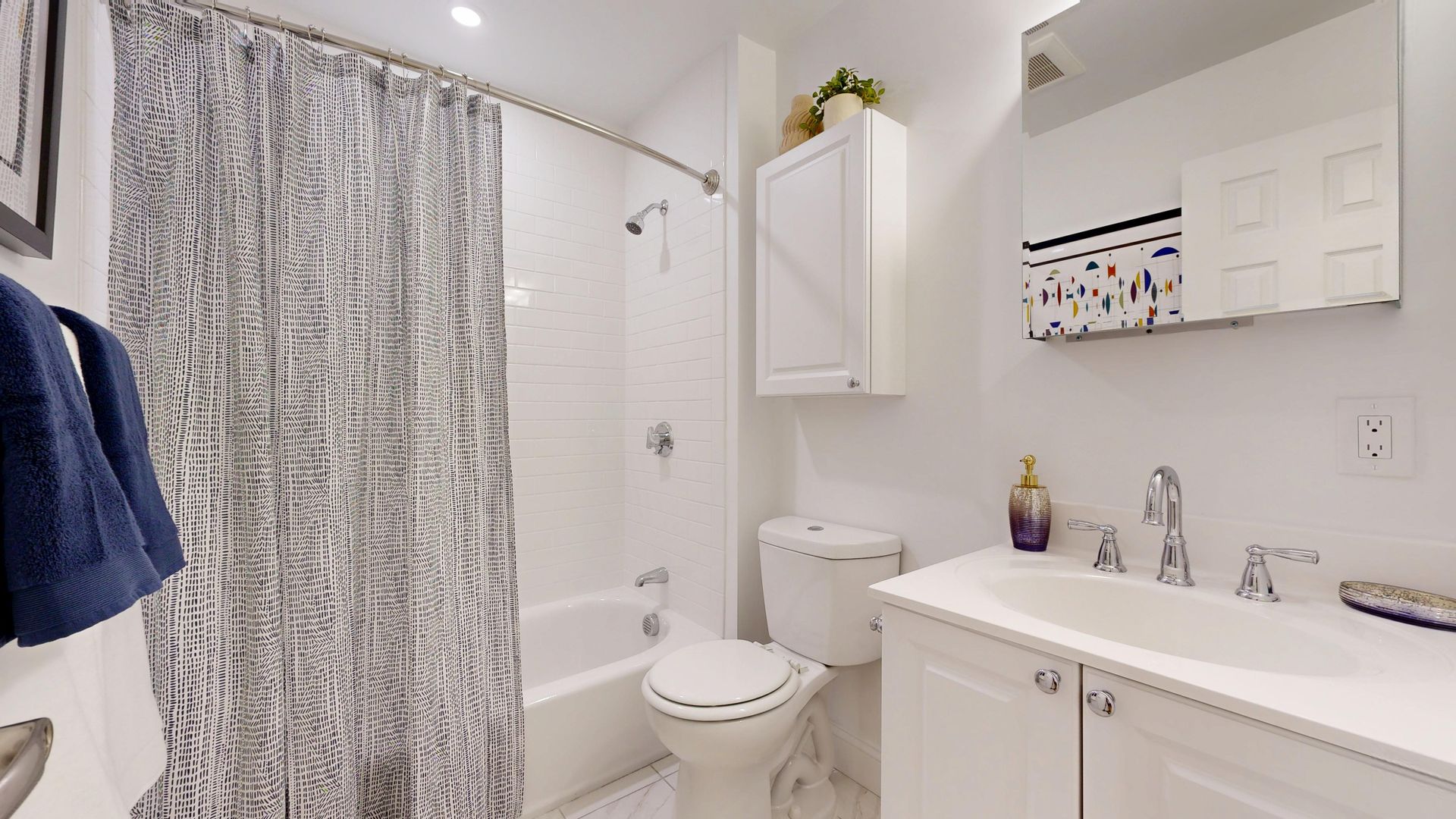 Bright white bathroom with shower curtain, sink, toilet, and mirror cabinet