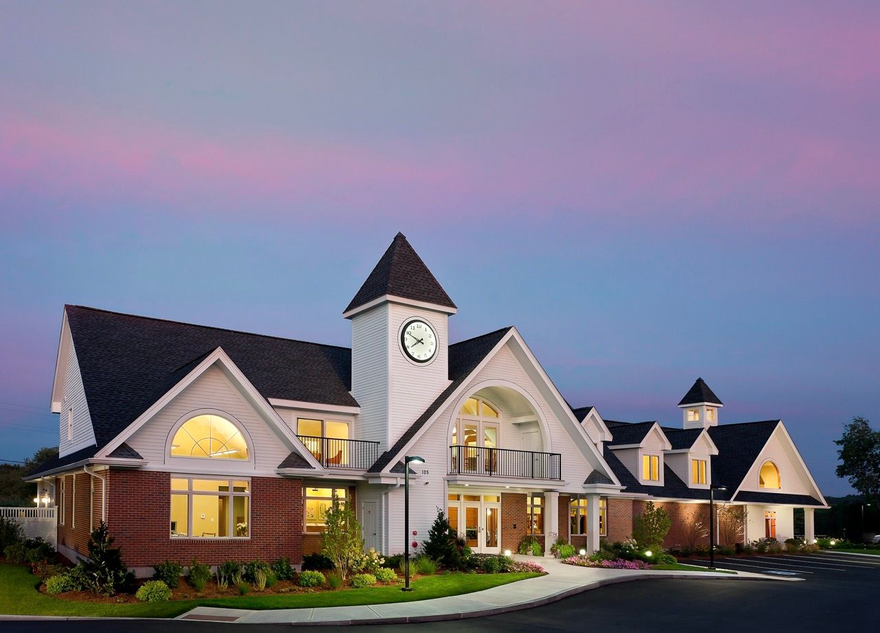 Exterior view of a multi-building apartment community with clock tower at dusk.