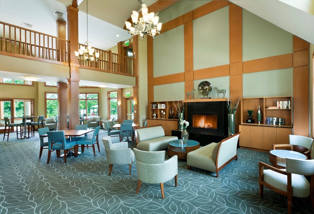 Spacious apartment community lobby with seating, a fireplace, and a mezzanine balcony.