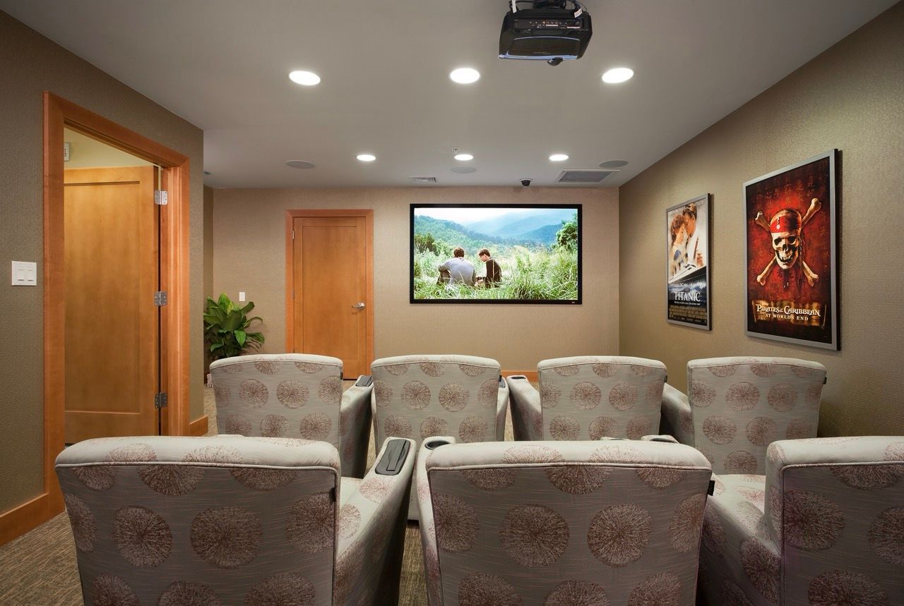 Indoor resident cinema with projector, screen, and rows of patterned seats.