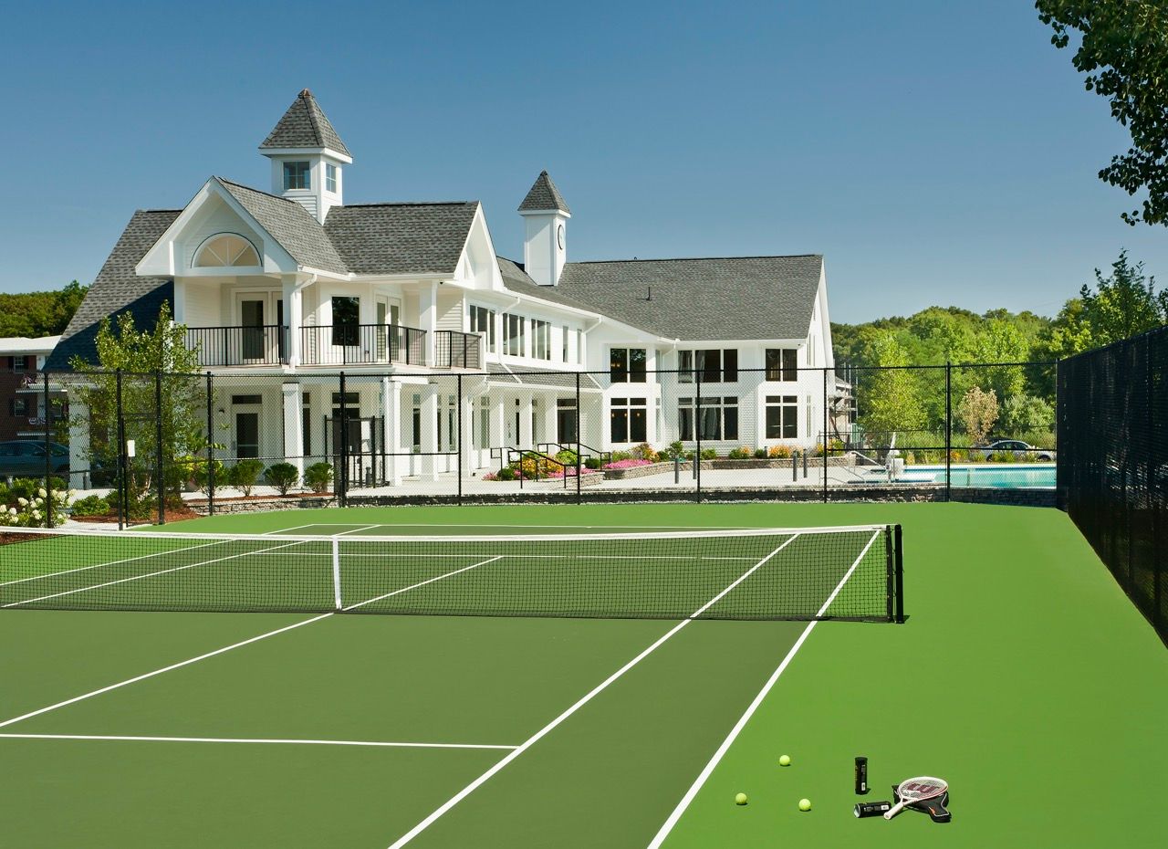 Exterior view of a multi-family community with a tennis court and clubhouse.