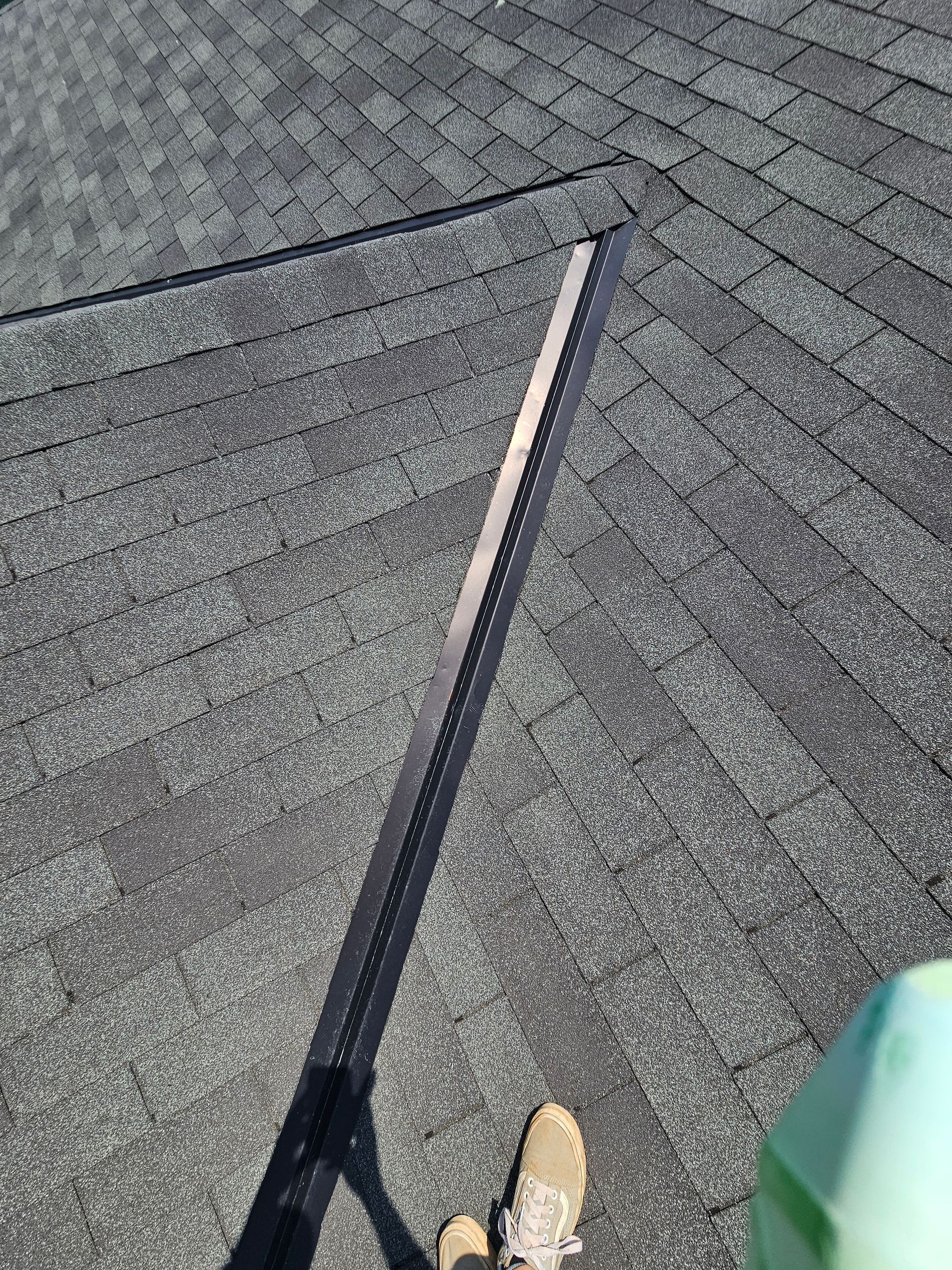 Black roof ridge vent on gray shingle roof.