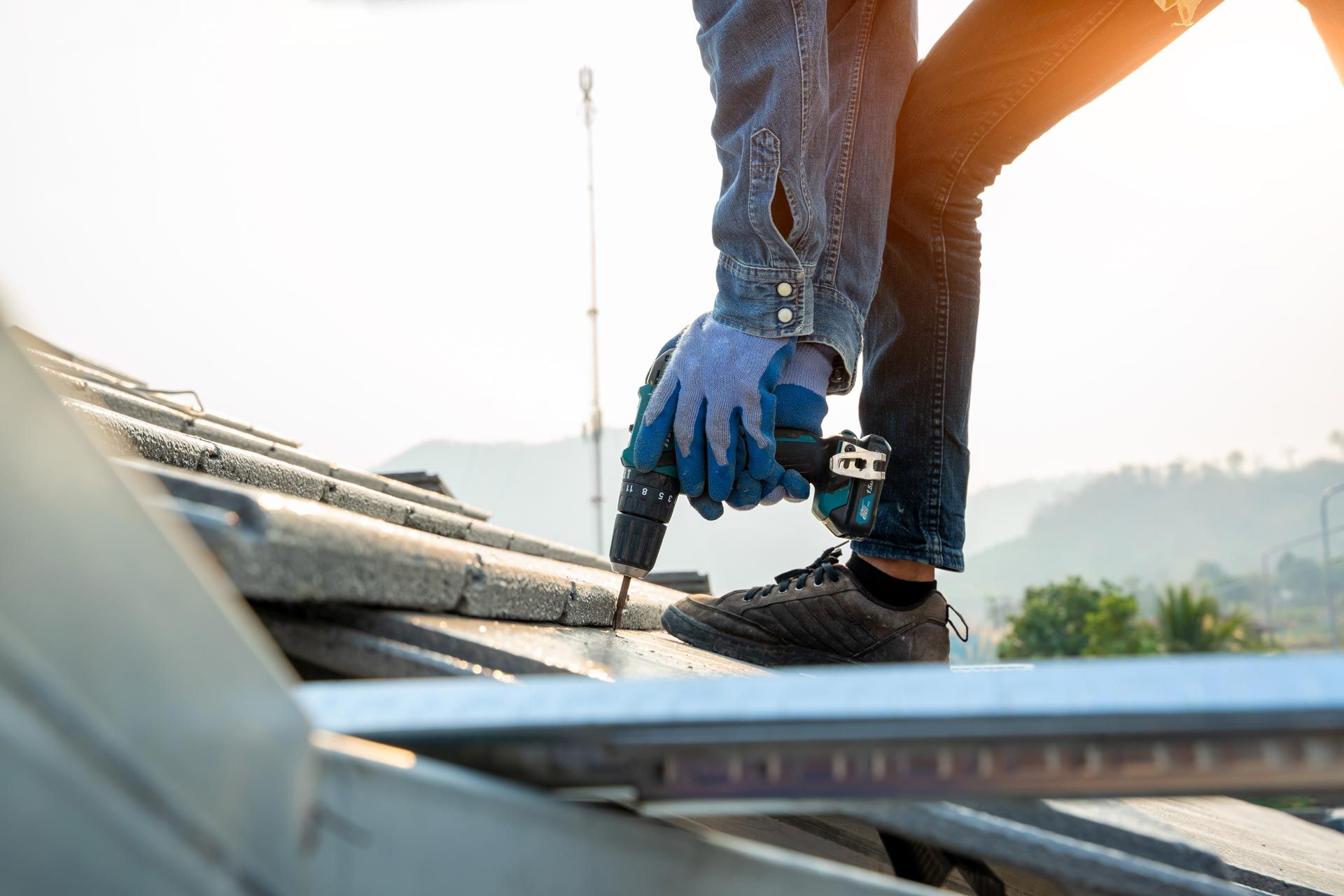 Commercial roofing work securing metal panels with a power drill.