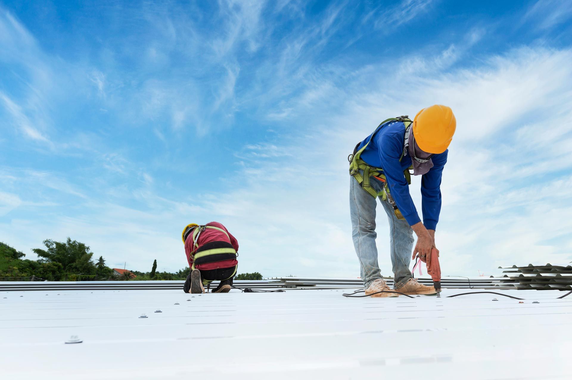 A commercial roofing crew installing metal panels on a large building roof.