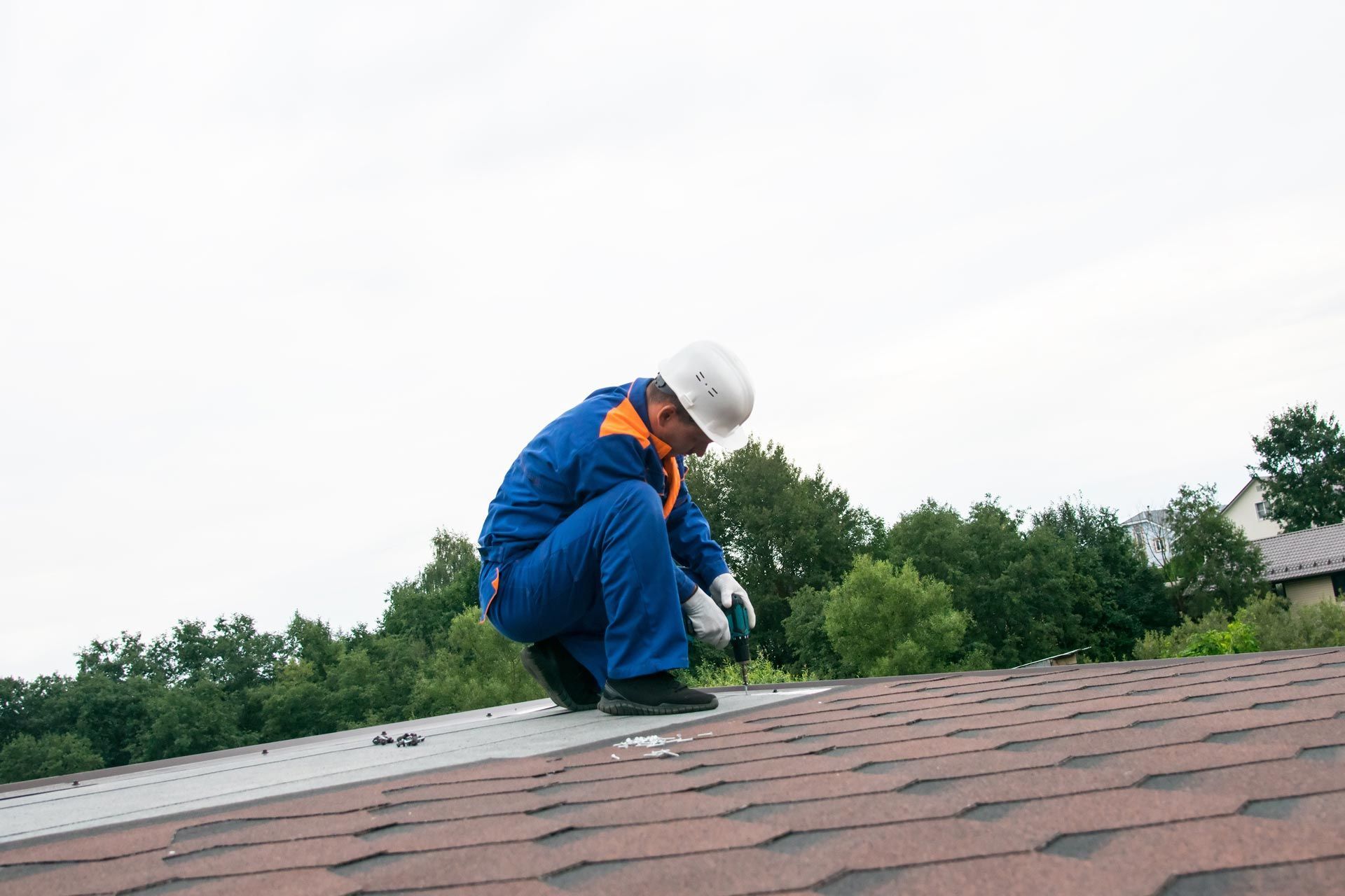 Roofing worker fastening metal panels on a commercial roof with power tools.