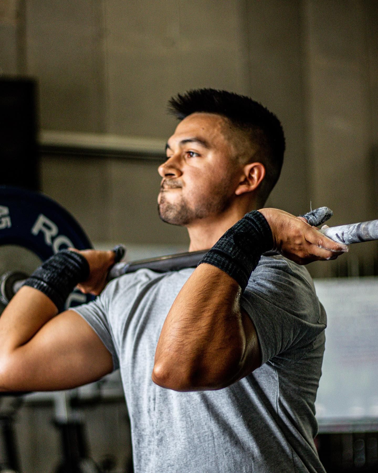 A man is holding a barbell over his head in a gym.