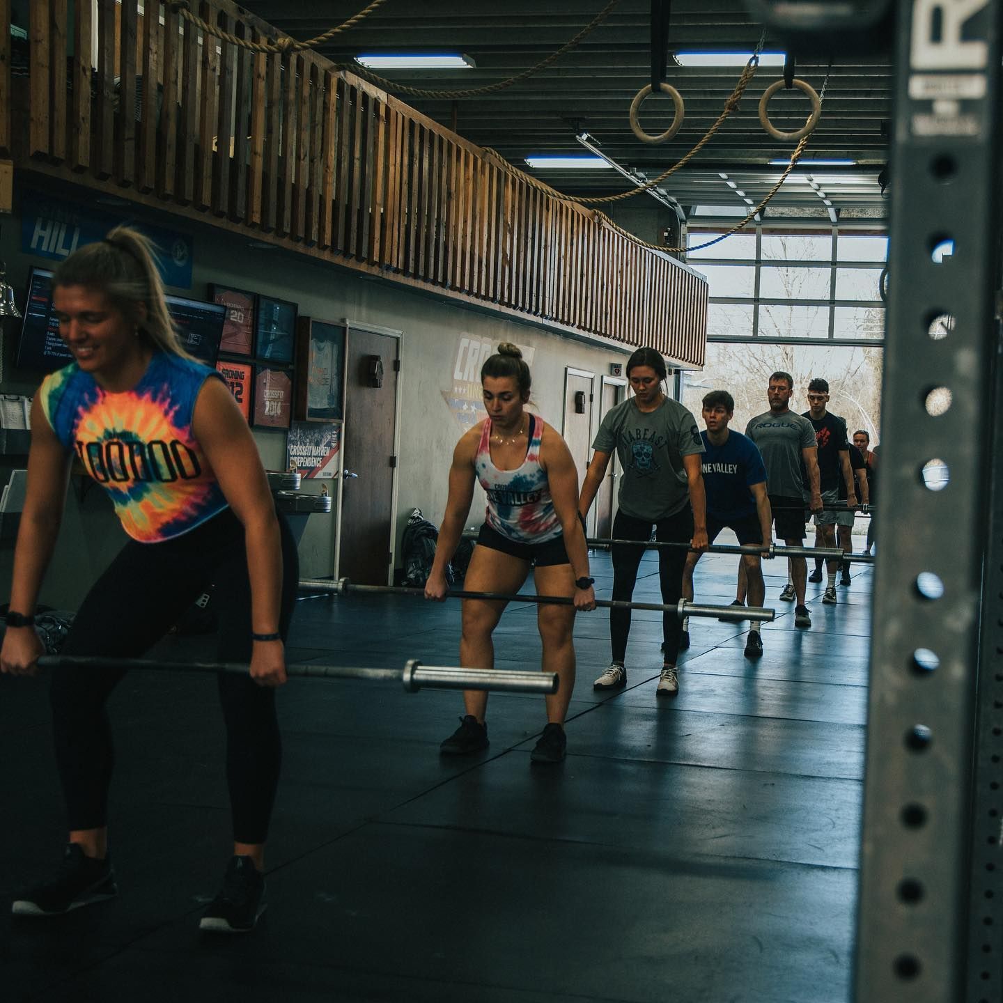 A group of people are lifting barbells in a gym.