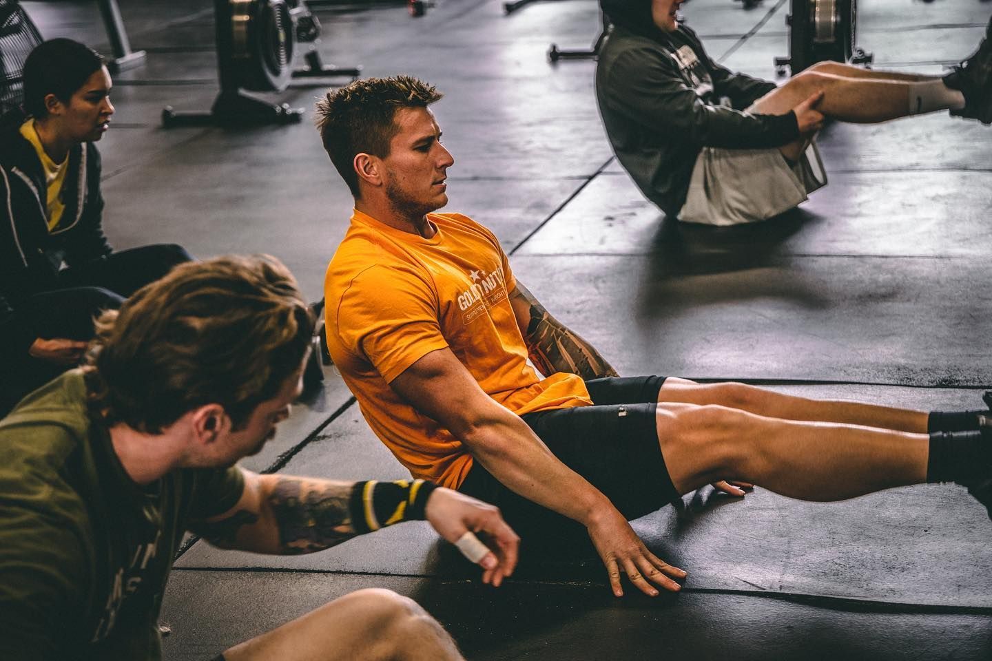 A group of men are doing sit ups on the floor in a gym.