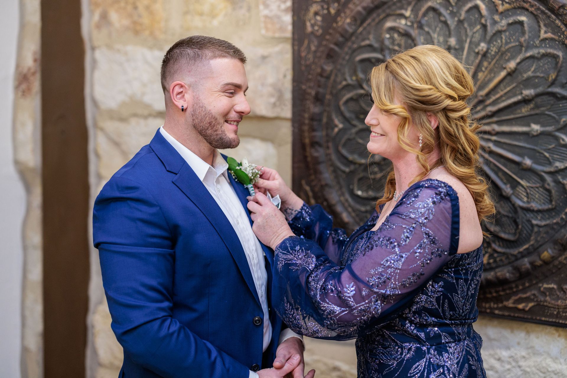 A woman is helping a groom get ready for his wedding.
