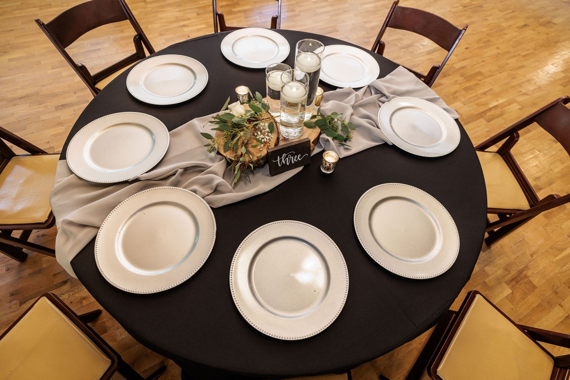 A round table with plates and candles on it.