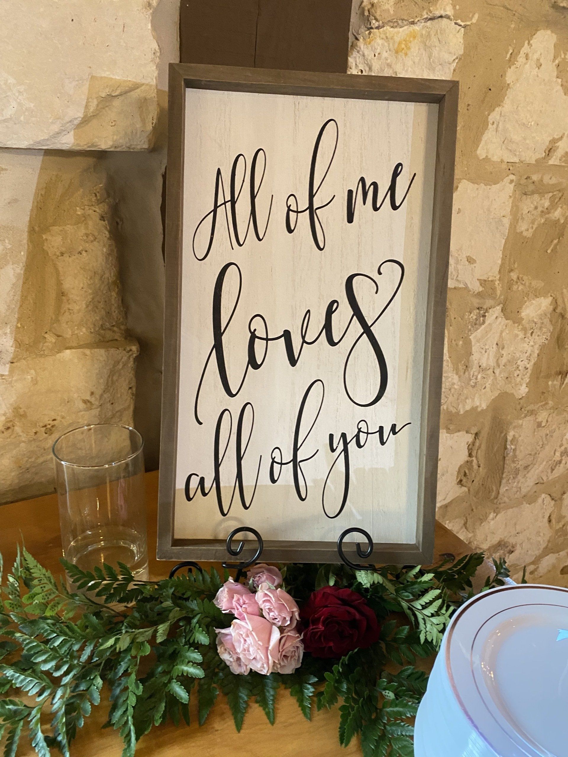 A sign that says `` all of me loves all of you '' is sitting on a table.