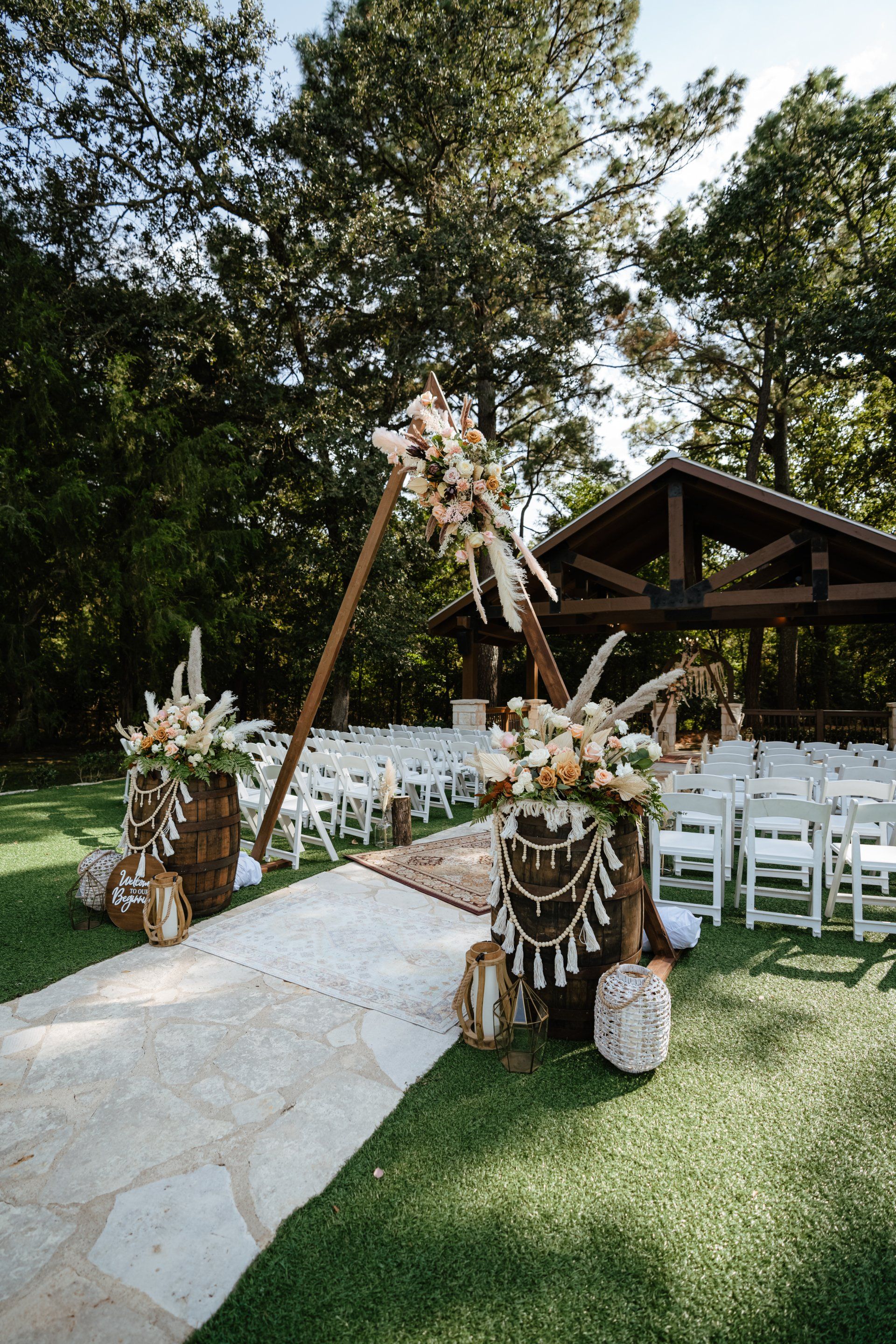 A row of white chairs are lined up in a grassy field for a wedding ceremony.