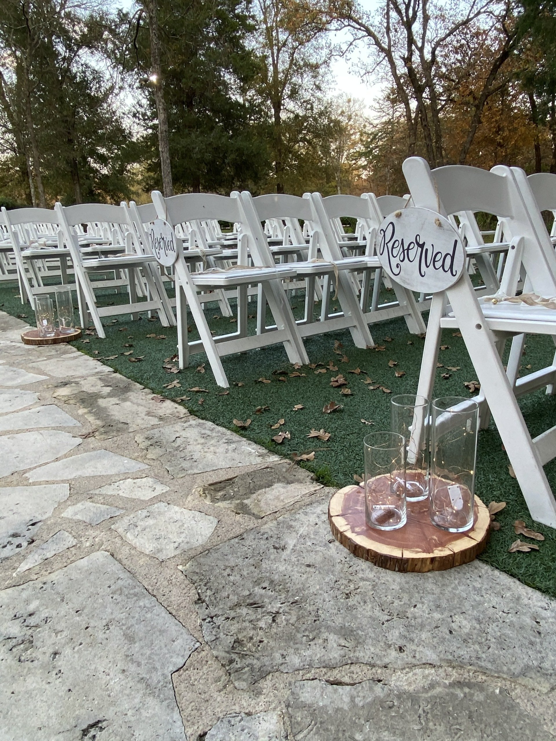 A row of white folding chairs are lined up for a wedding ceremony.