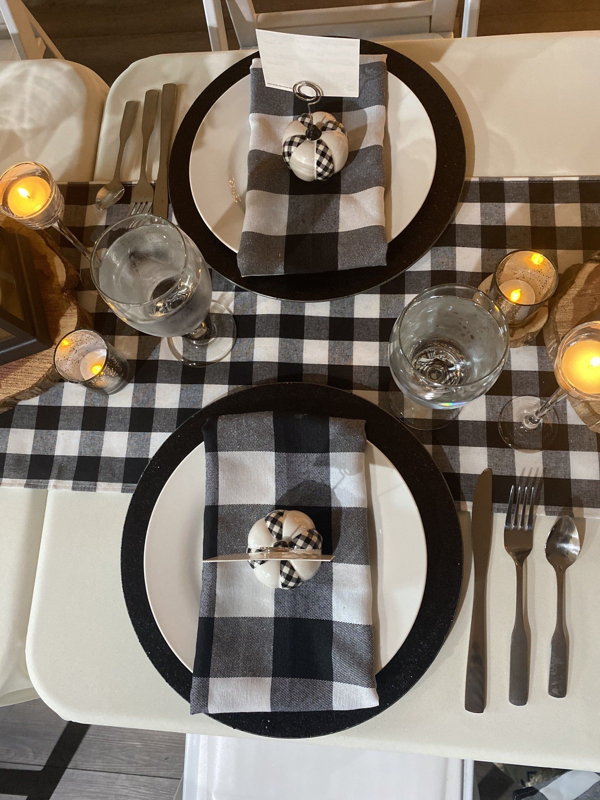 A table with plates , napkins , utensils and candles on it.
