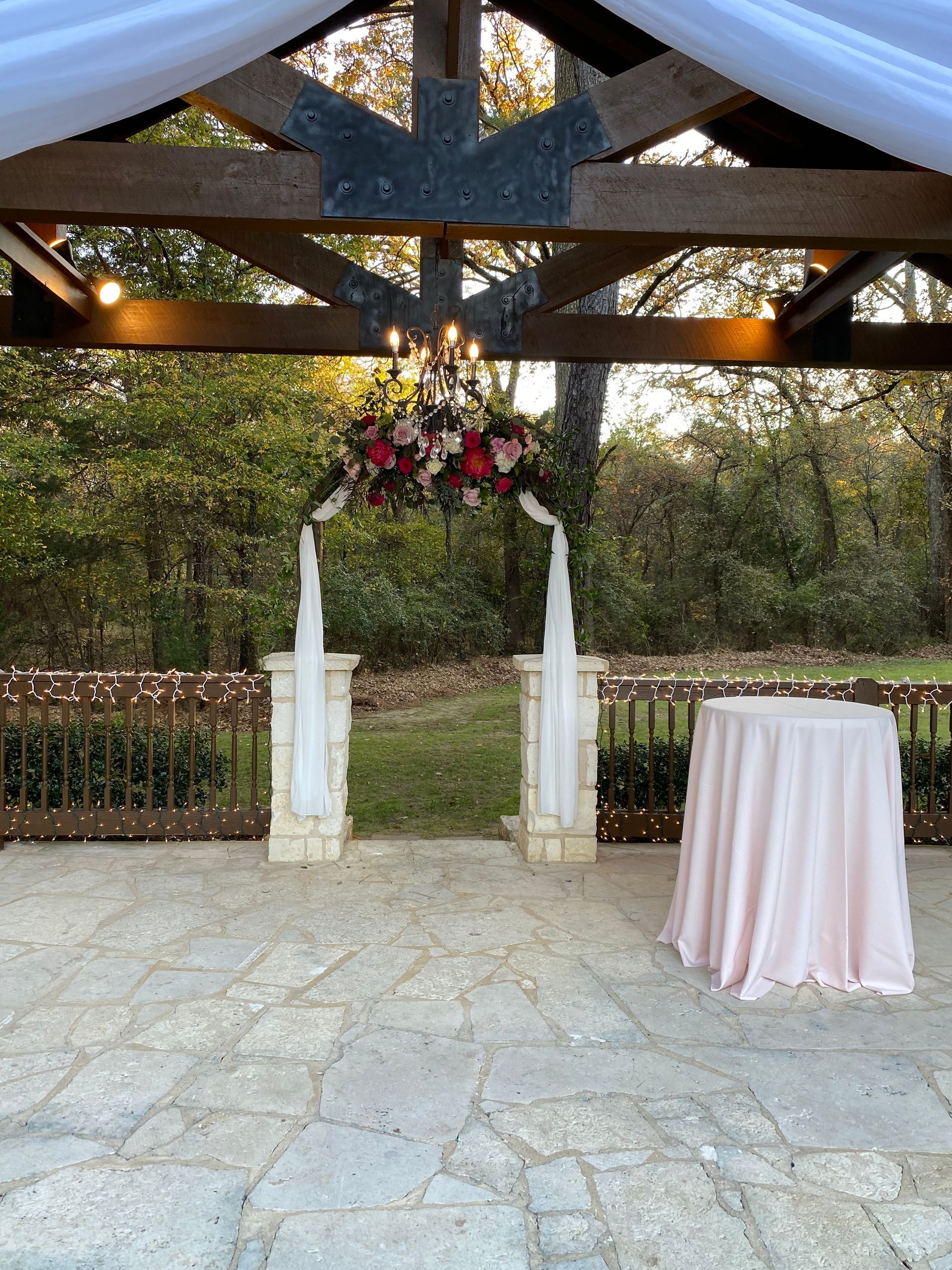 There is a table with a pink tablecloth in front of a gazebo.