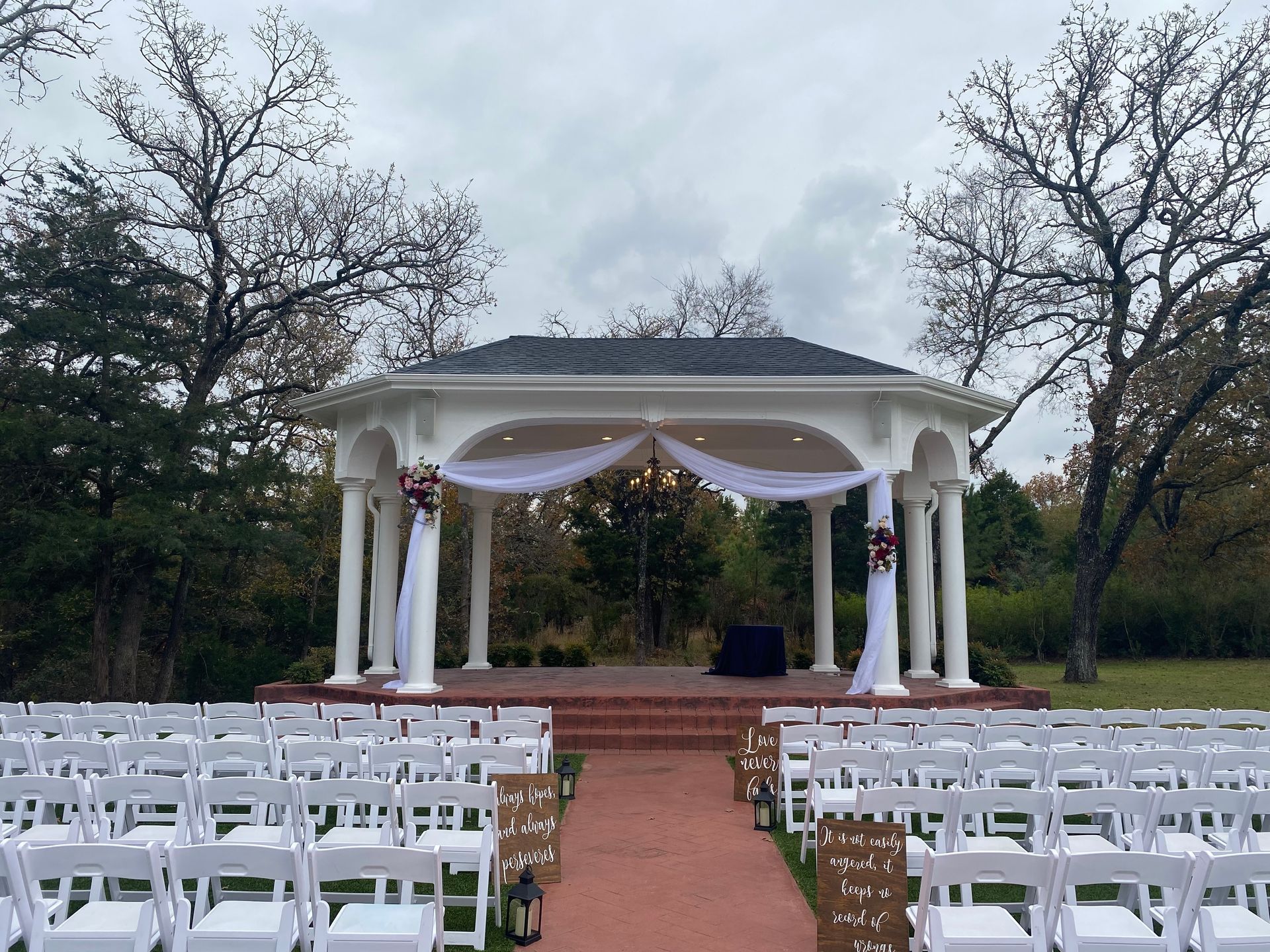 Rows of white chairs are lined up in front of a gazebo for a wedding ceremony.