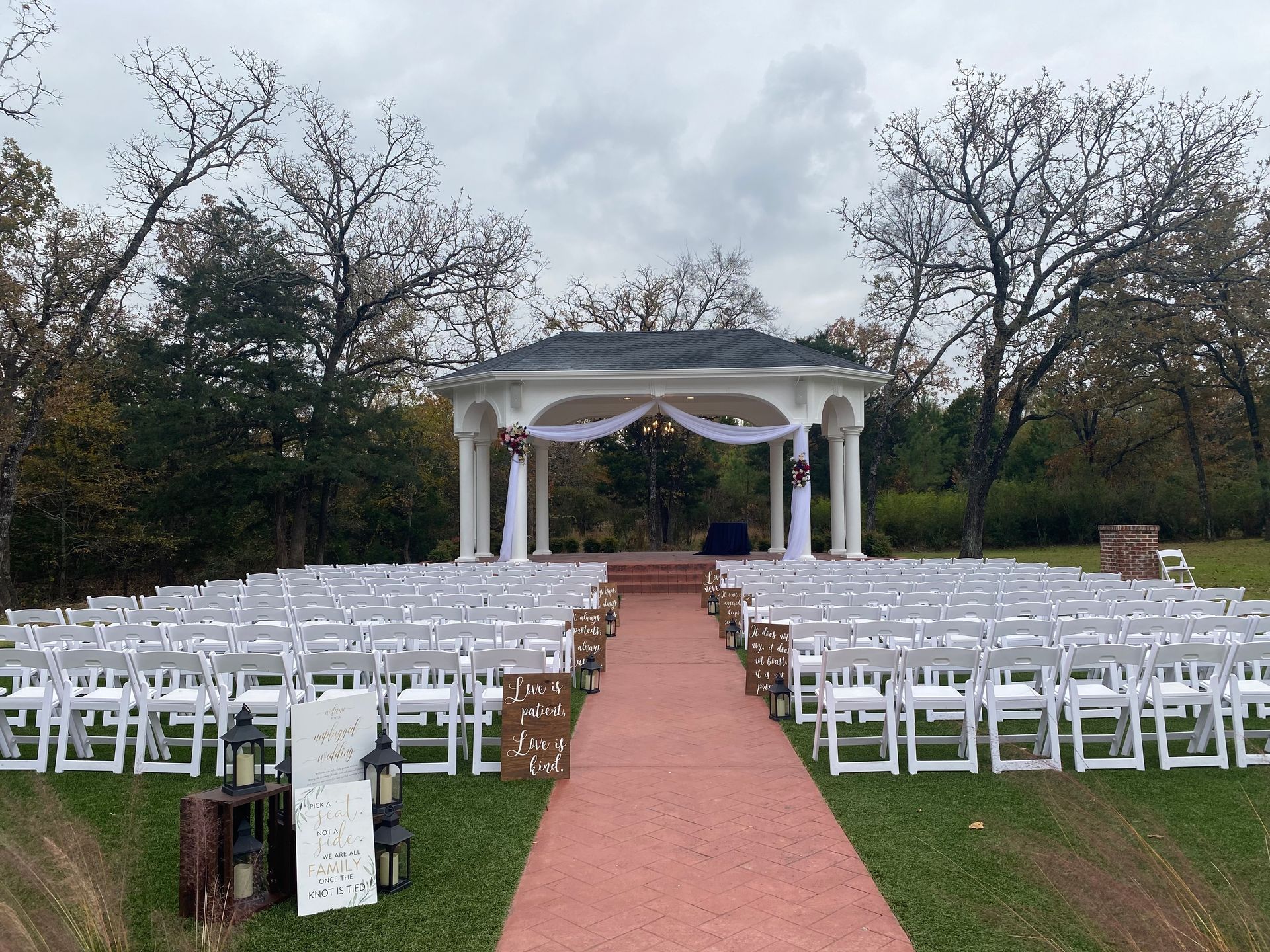 Rows of white chairs are lined up in front of a gazebo for a wedding ceremony.