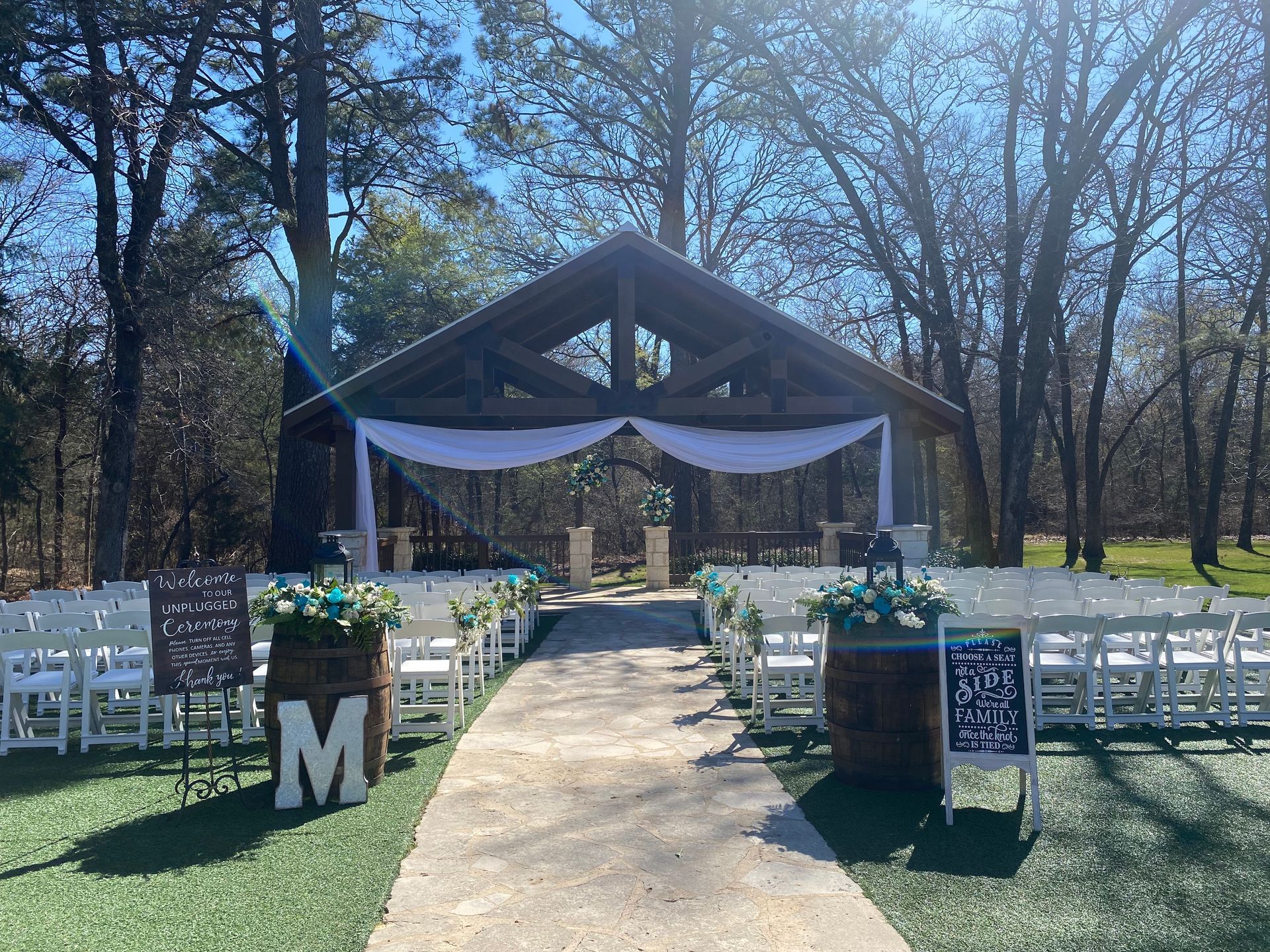 A wedding ceremony is taking place under a gazebo in the woods.