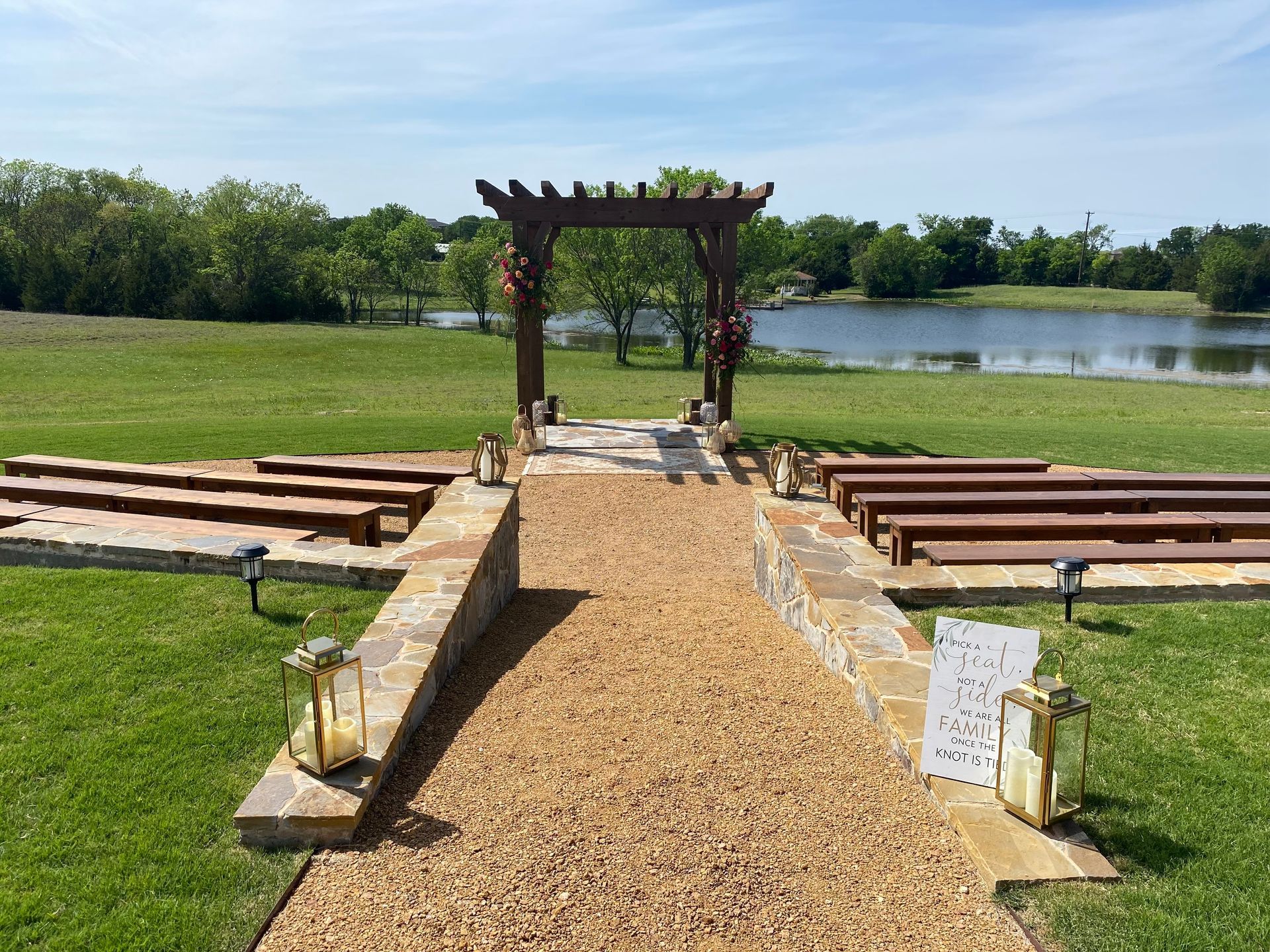 A gravel path leading to a wooden archway overlooking a lake.