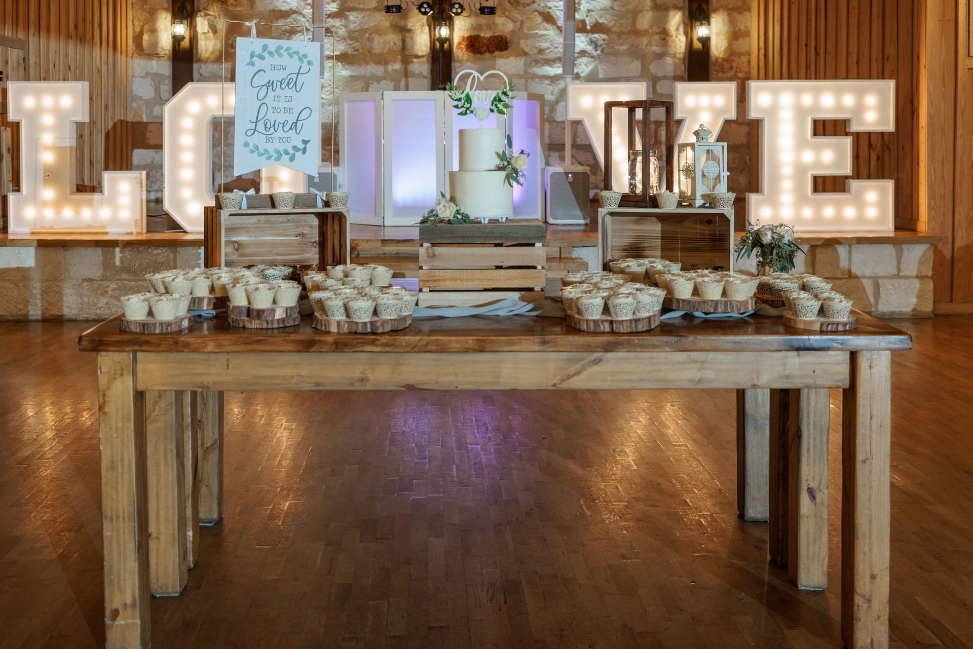 A wooden table with cupcakes and a cake on it.