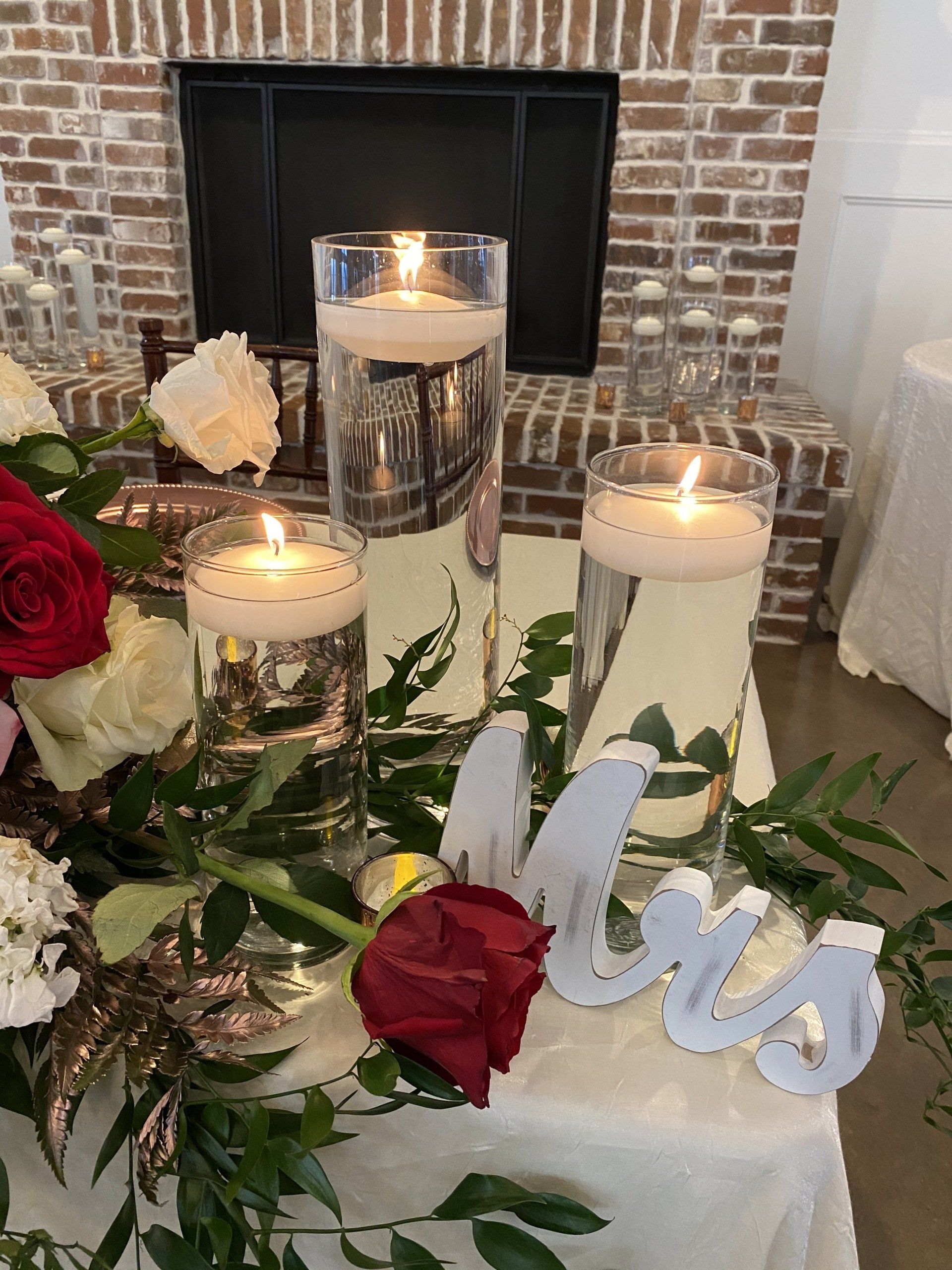 A table with candles and flowers in front of a fireplace