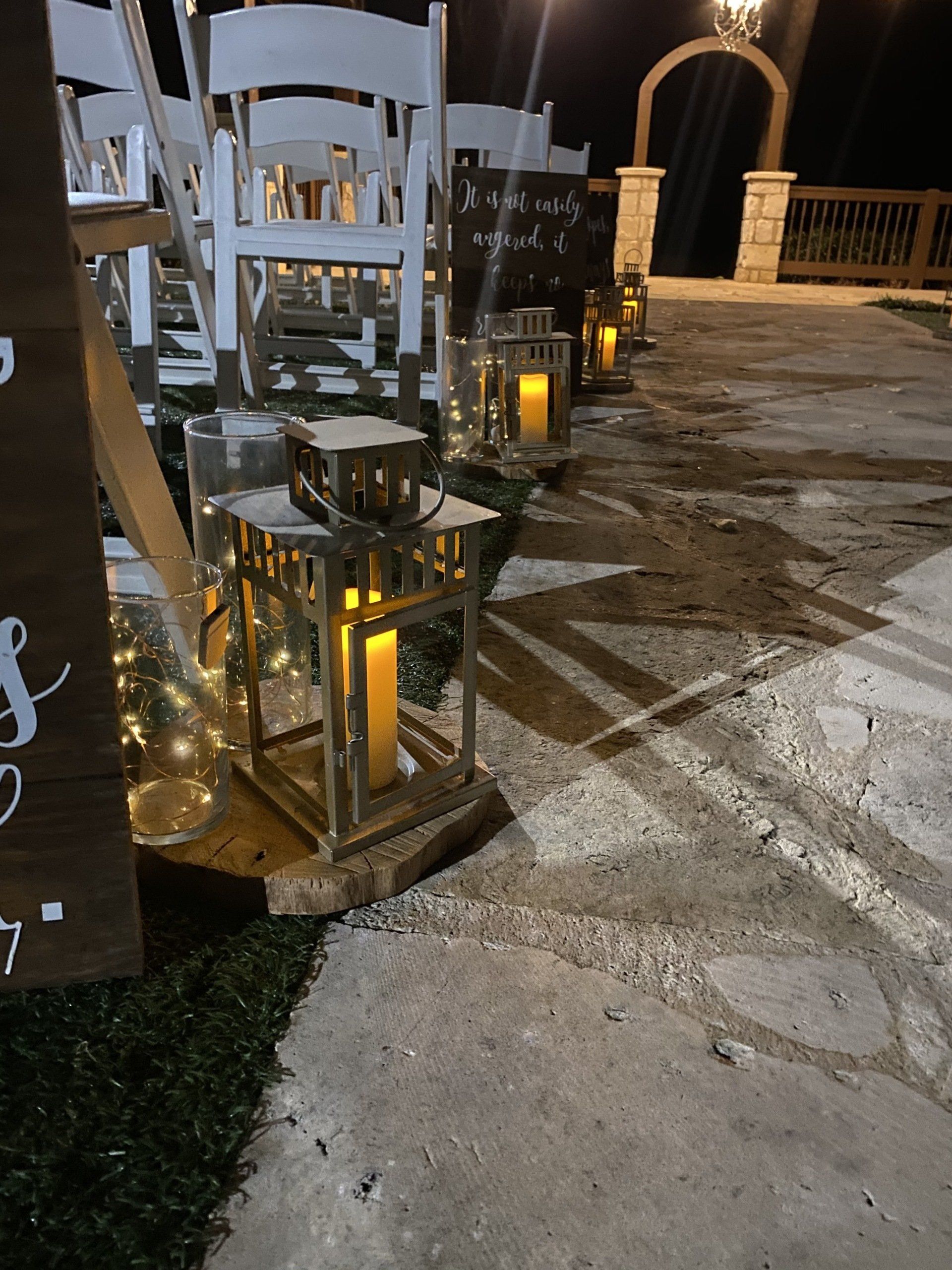 A row of lanterns with candles in them are lined up on a sidewalk.