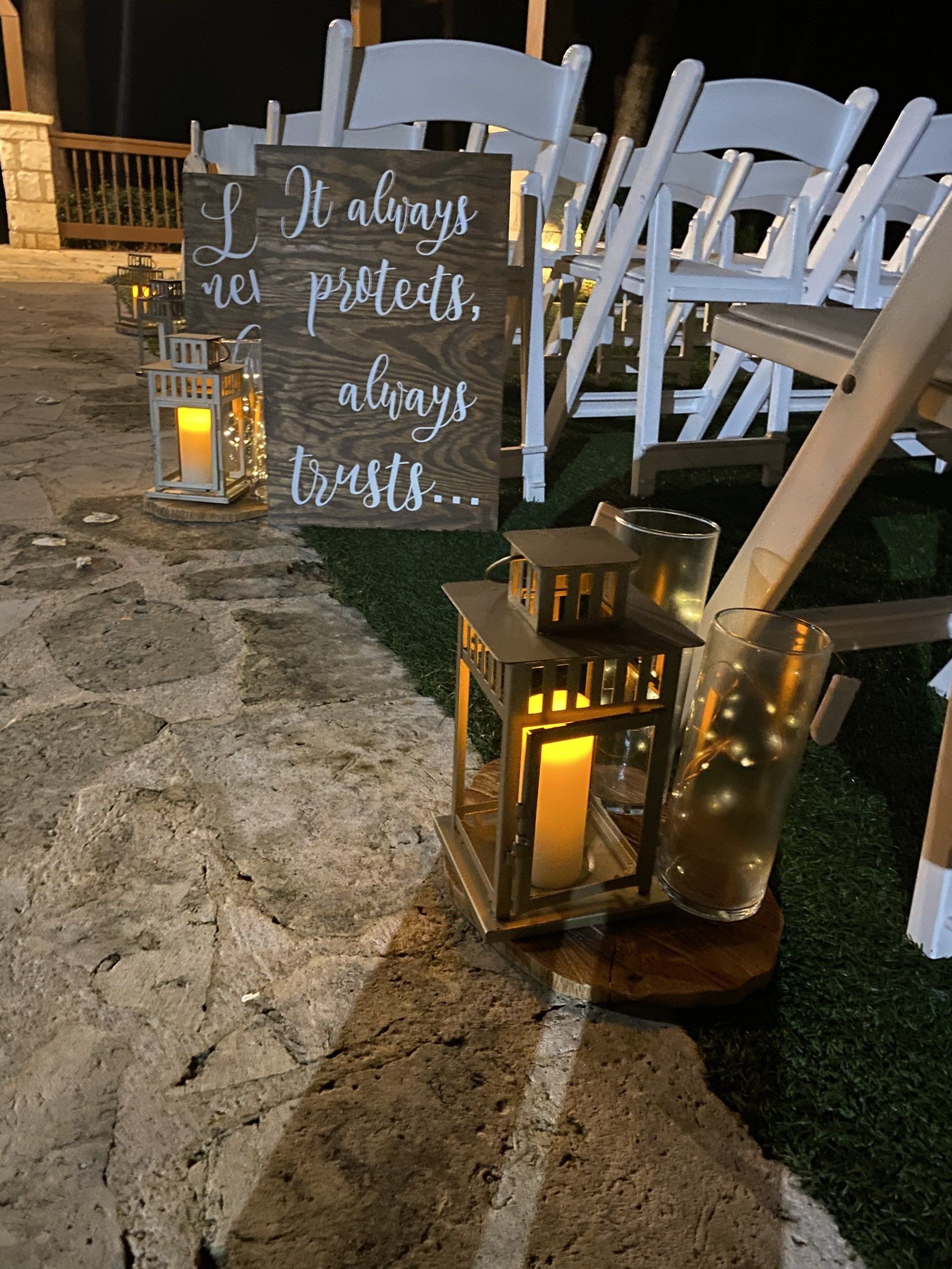 A sign that says `` it always protects , always trusts '' is sitting on the ground next to lanterns.