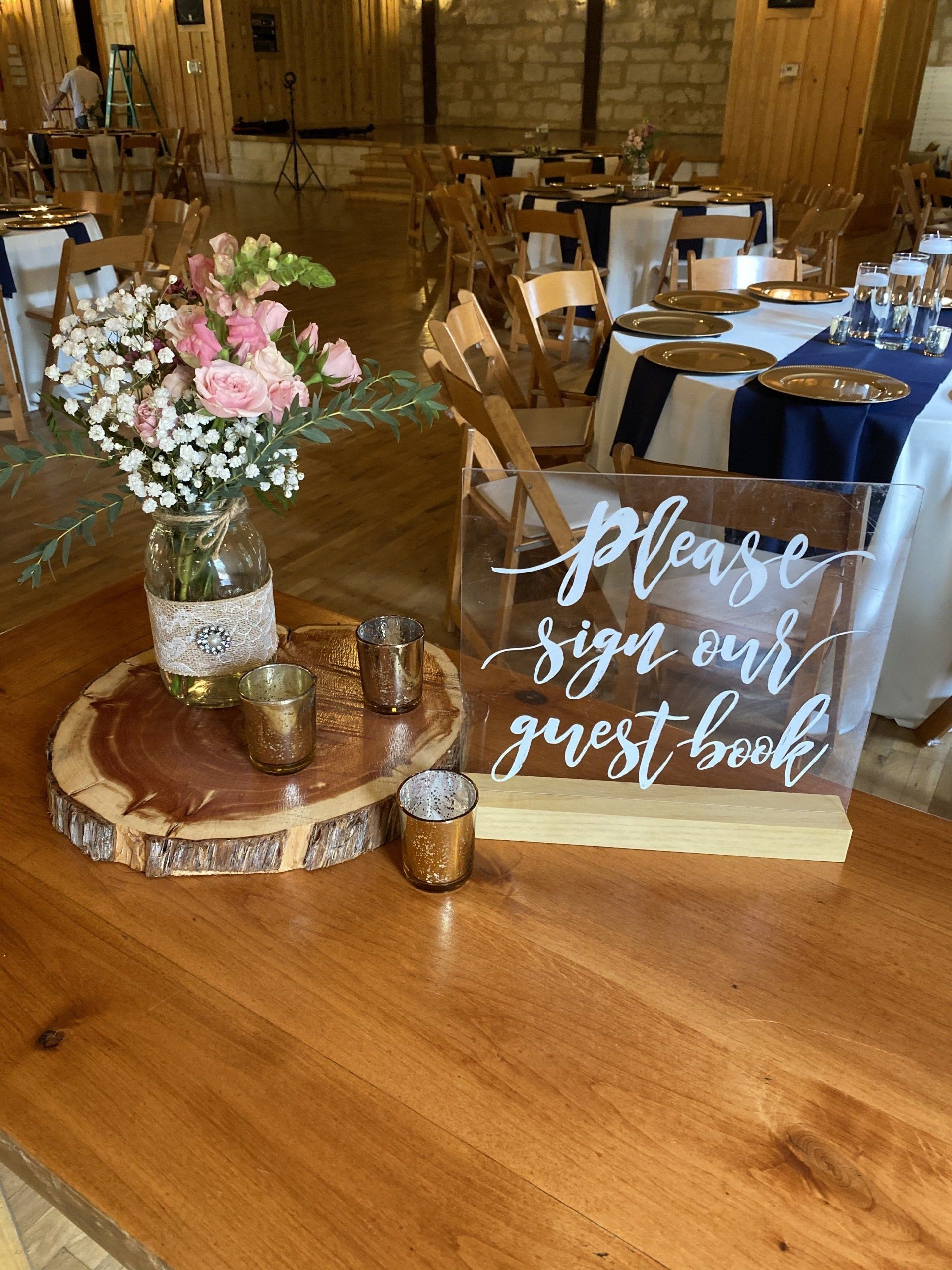 A wooden table with a sign on it that says `` please sign our guest book ''.