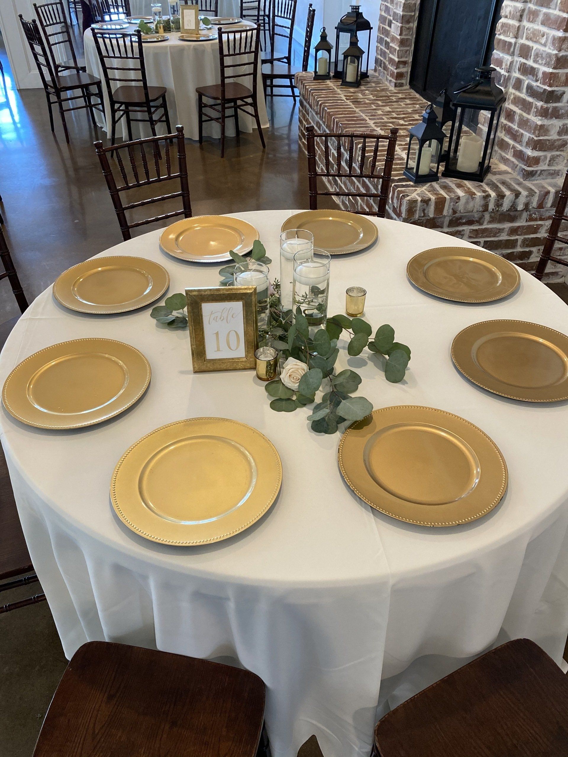 A round table with gold plates and a white table cloth
