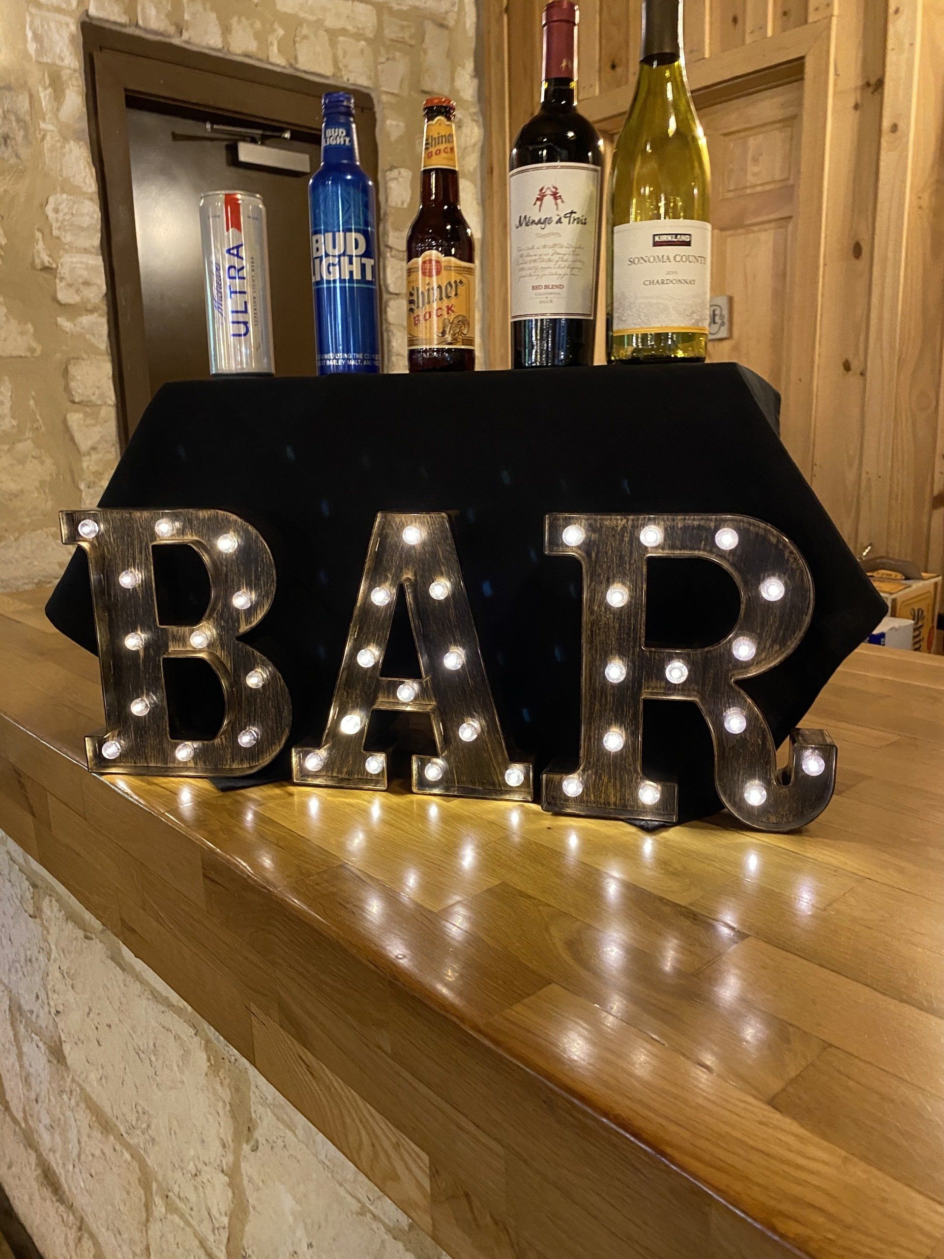 A bar sign with lights on it is sitting on a wooden counter.