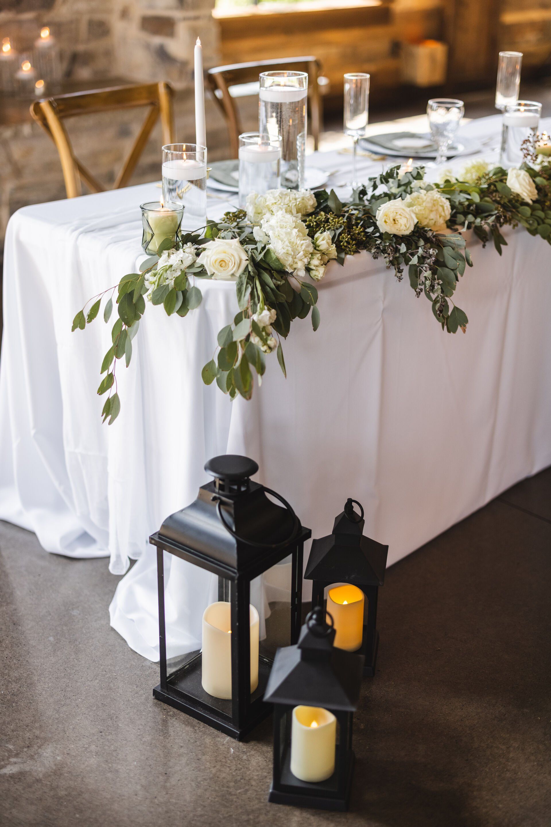 The table is decorated with lanterns and flowers for a wedding reception.