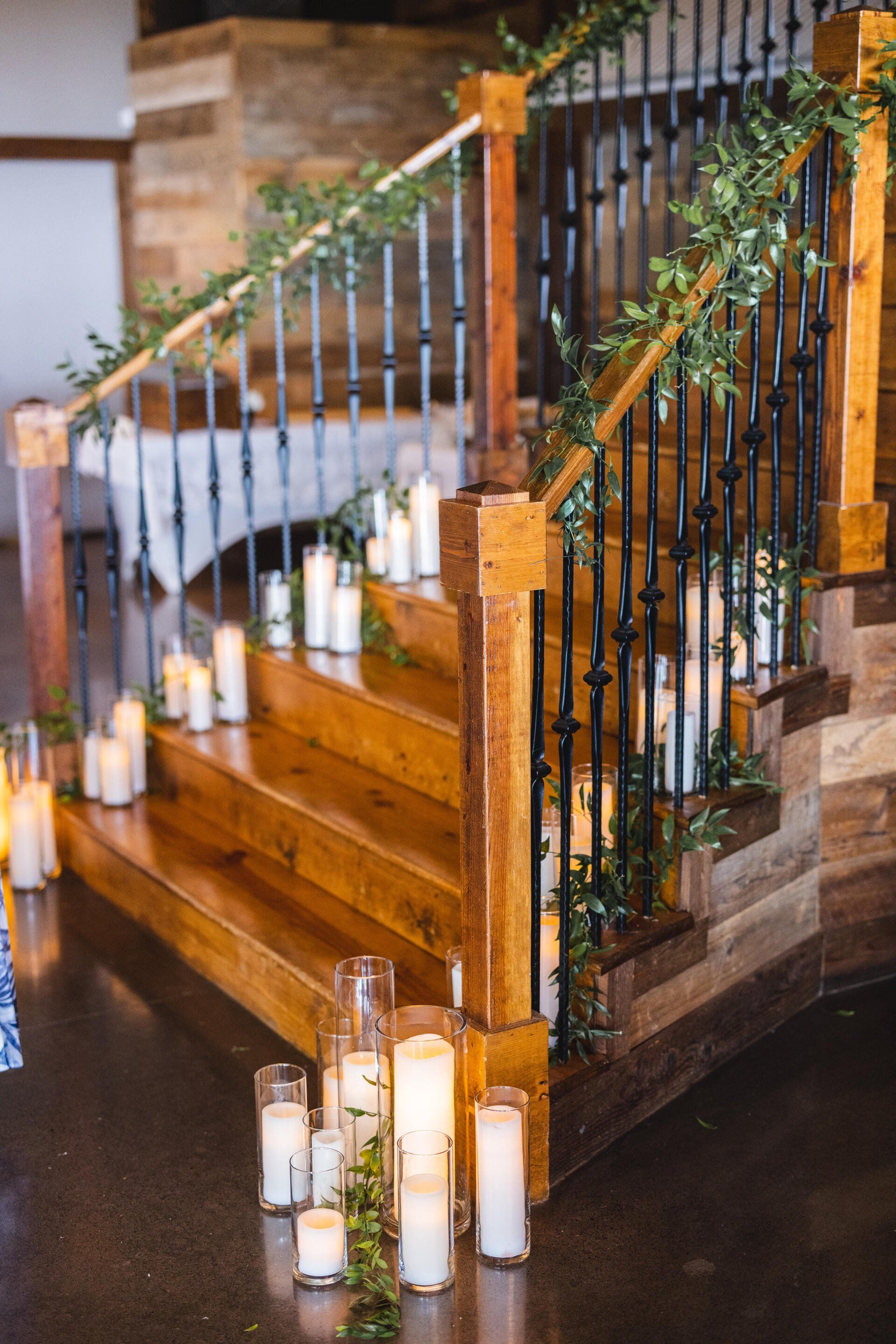 A wooden staircase decorated with candles and greenery.