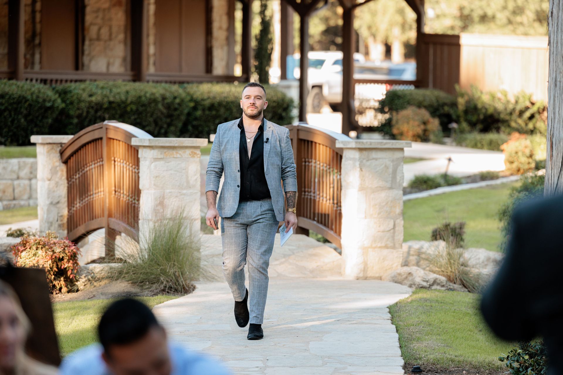 A man in a suit is walking across a bridge.