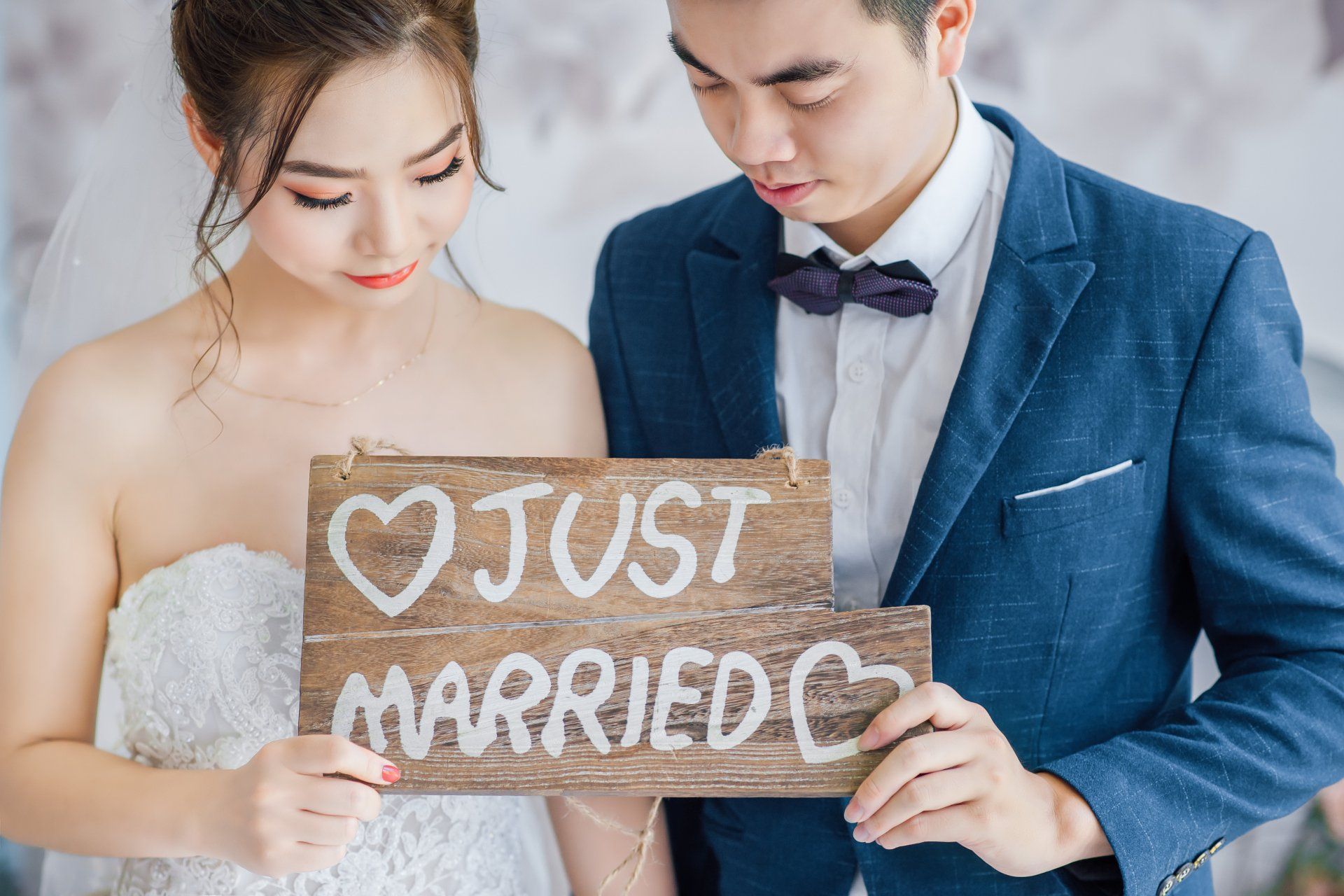 A bride and groom are holding a wooden sign that says `` just married ''.