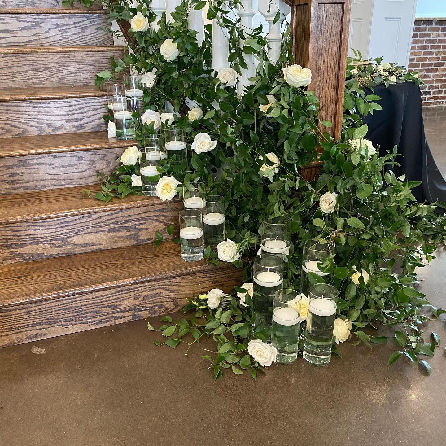 A set of wooden stairs decorated with white flowers and candles.