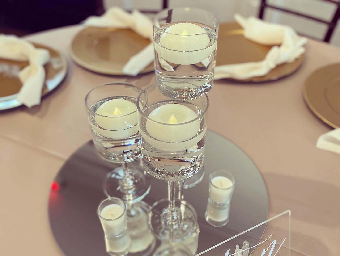 A table setting with wine glasses filled with water and candles.