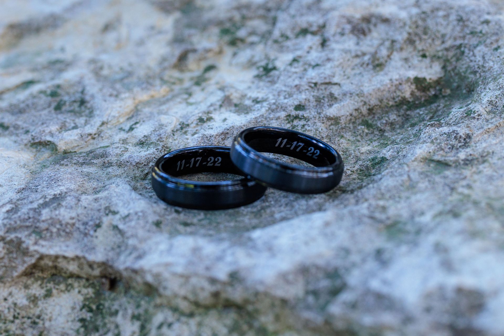 Two black wedding bands engraved with 