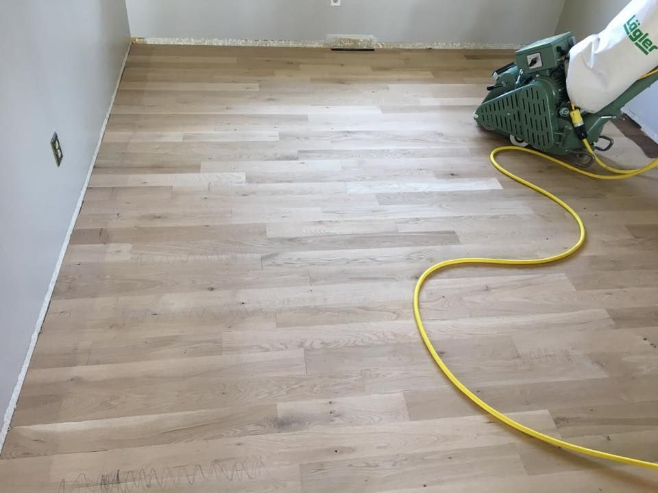 A wooden floor is being sanded with a machine.