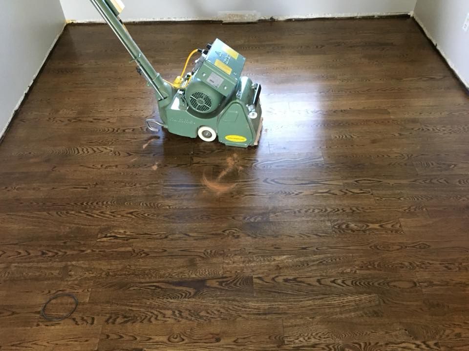 A machine is sanding a wooden floor in a room.