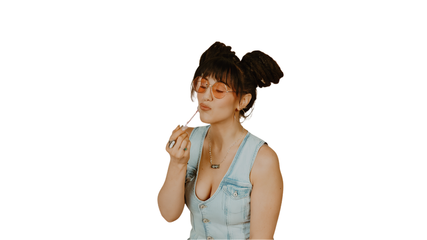 Woman in a light blue top blowing bubbles against a white background.