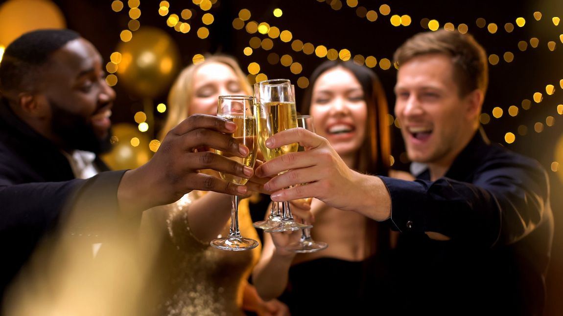 Happy multi-ethnic company clinking beverage glasses