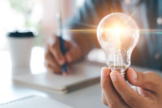 Man sitting at desk holding a light bulb