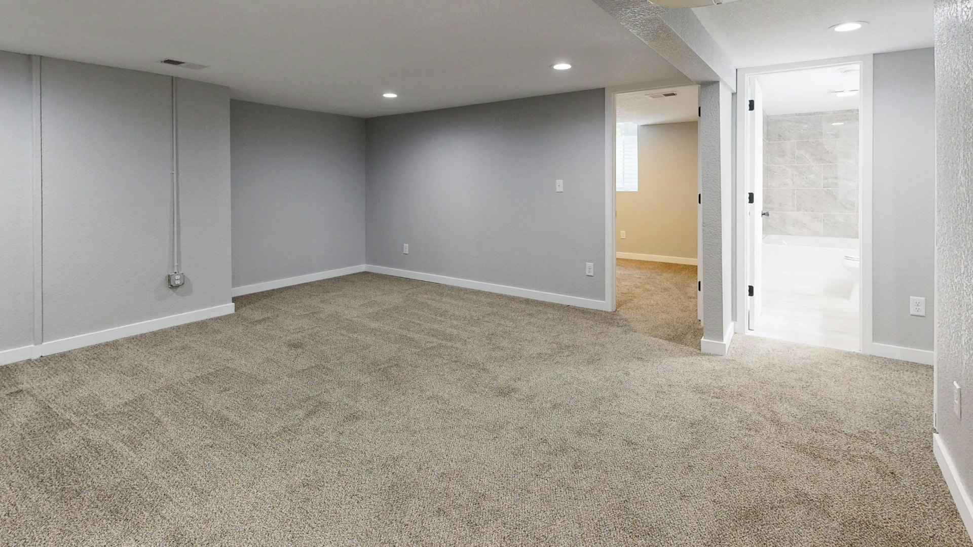 Spacious living room with beige carpet, white trim, a fireplace, and a light-colored sectional sofa.