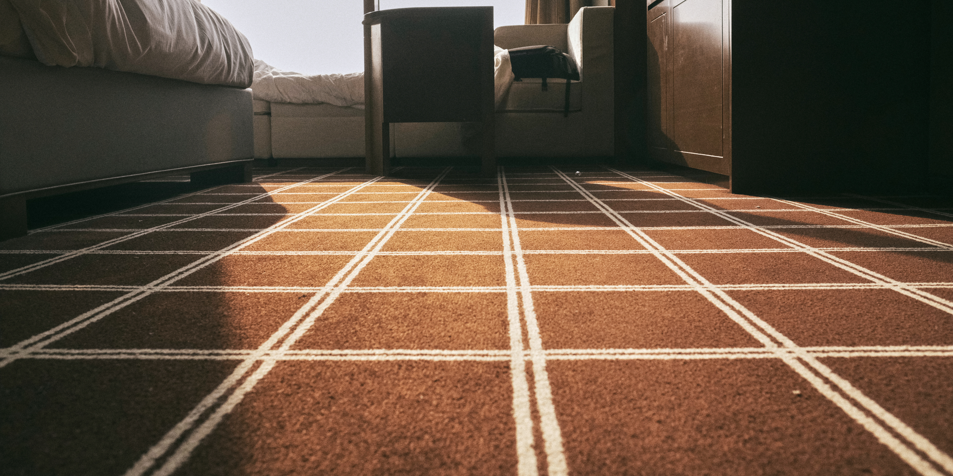 Empty living room with beige walls, carpet, and a bay window.