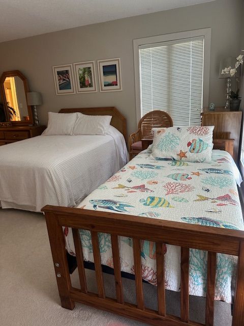 Bedroom with a double bed and a twin bed, both with white bedding. Fish-patterned quilt on twin bed. Beige walls.