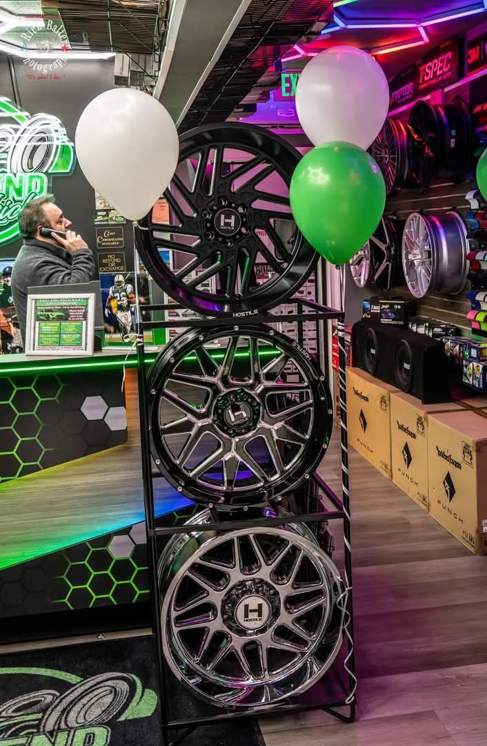 Display of custom car wheels with white and green balloons in a shop or trade show booth | East End Auto Kicks