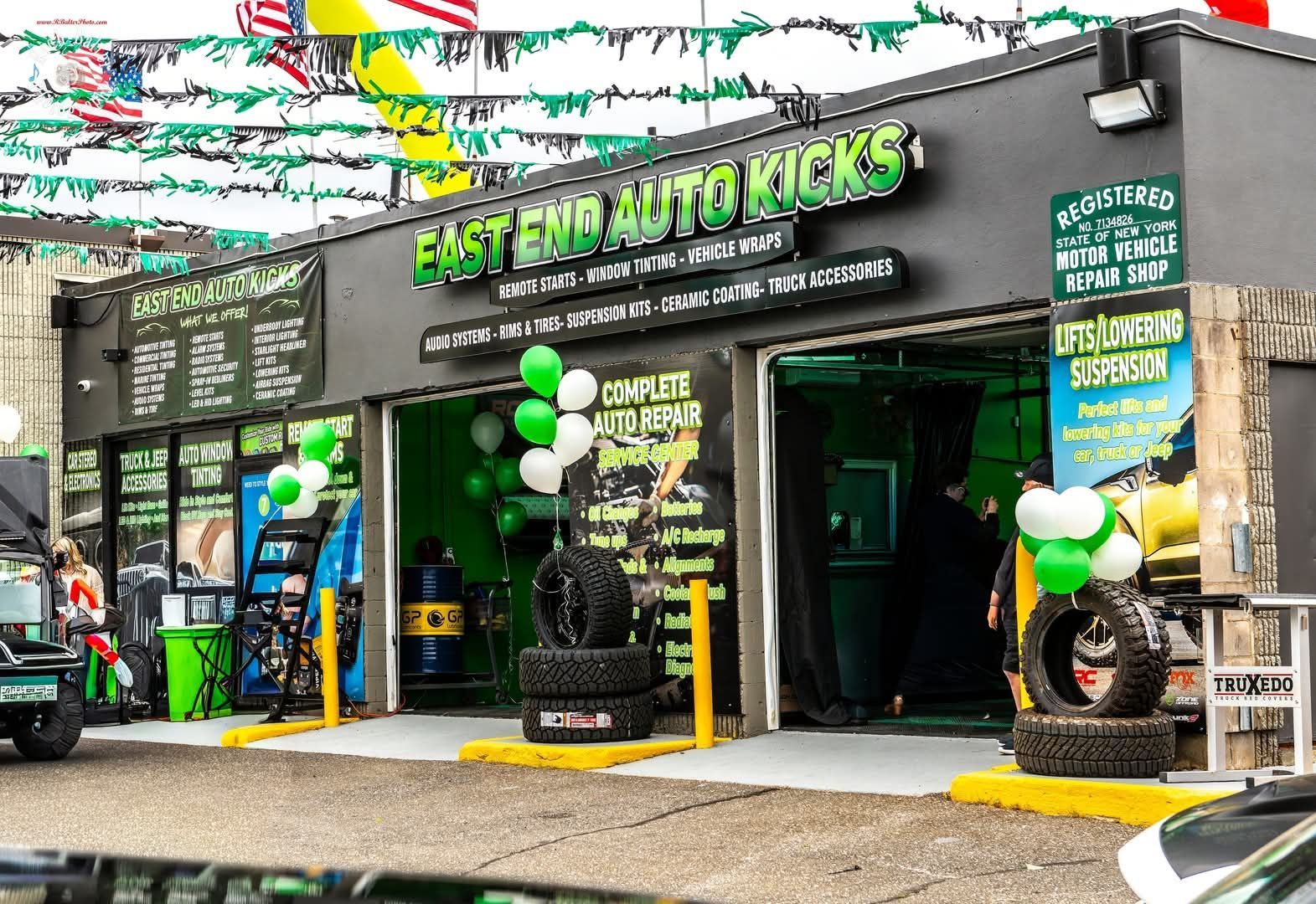 Exterior of East End Auto Elecs garage with green-and-black signage and balloons at the entrance | East End Auto Kicks